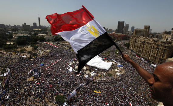 An Egyptian waves a national flag as protesters gather in Tahrir square in Cairo